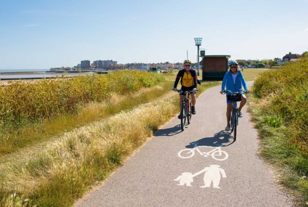 Lady and man cycling along path above beach