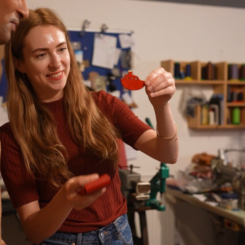 A leathercraft workshop experience on the Isle of Thanet featuring an instructor showing a handmade leather boat.