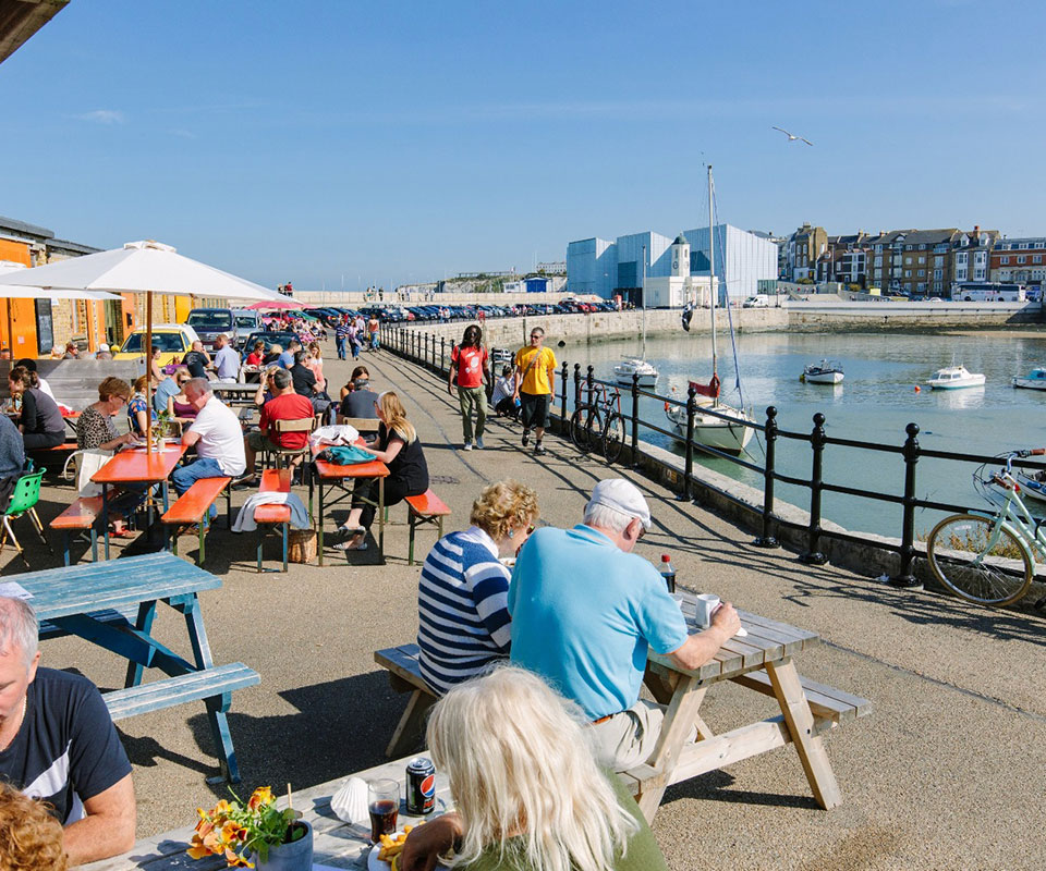 Bustling outdoor dining area on the Margate Harbour Arm with views of the harbor and Turner Contemporary.