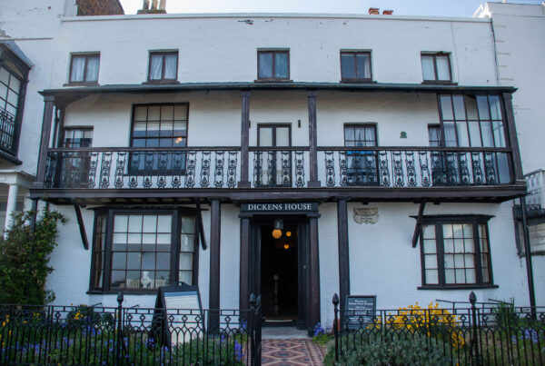 Front exterior view of museum with Tudor and Georgian elements. White fronted, wooden windows, balcony on first floor, flowerbeds either side of central door