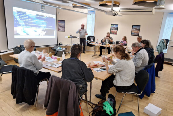 A group of participants in a bright training room engaged in a first aid and accessibility workshop.