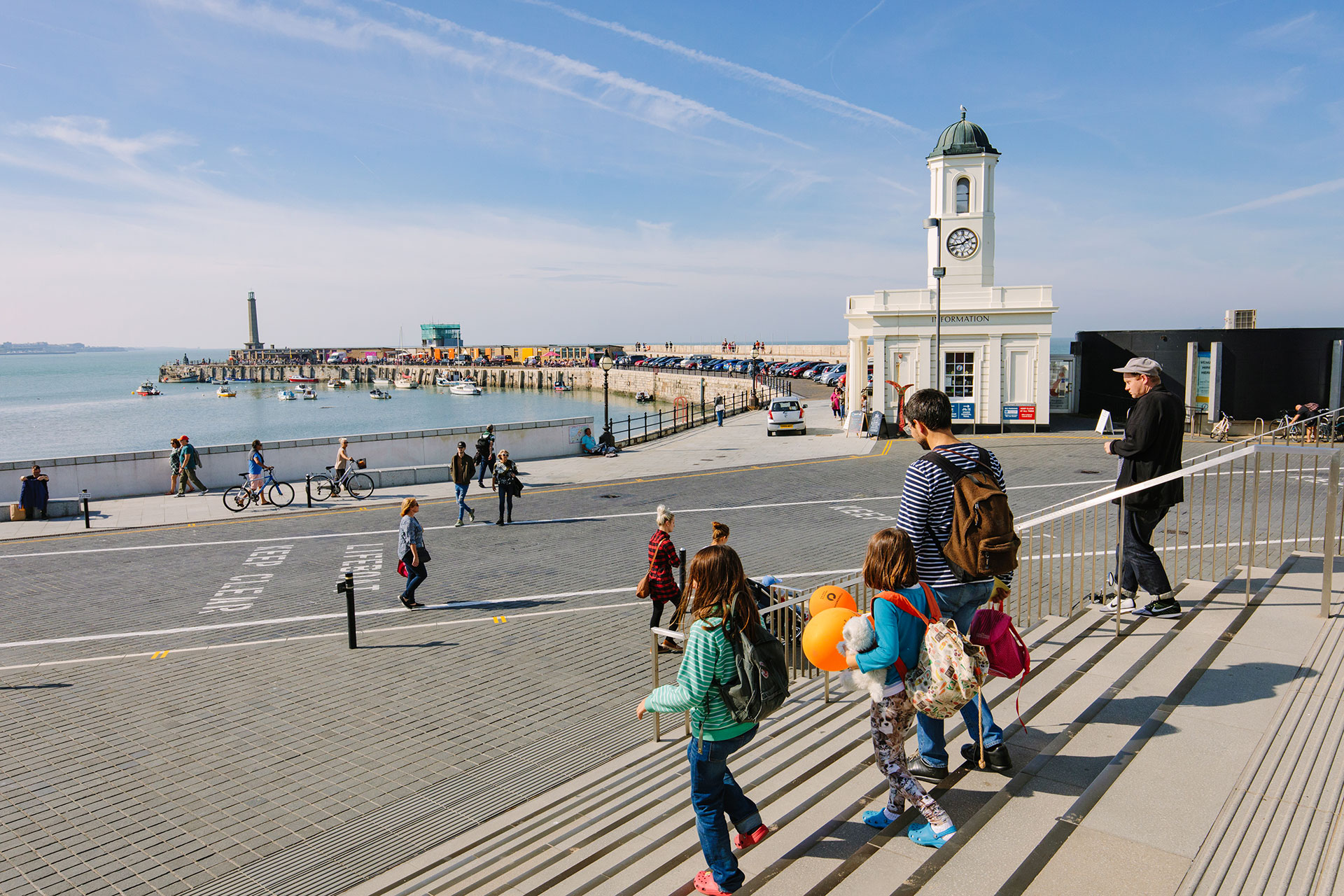People walking toward the Margate Harbour Arm and the Droit House information center on a clear day.