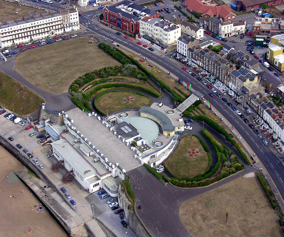 Aerial view of entertainment venue built into cliffs, gardens either side and promenade in front