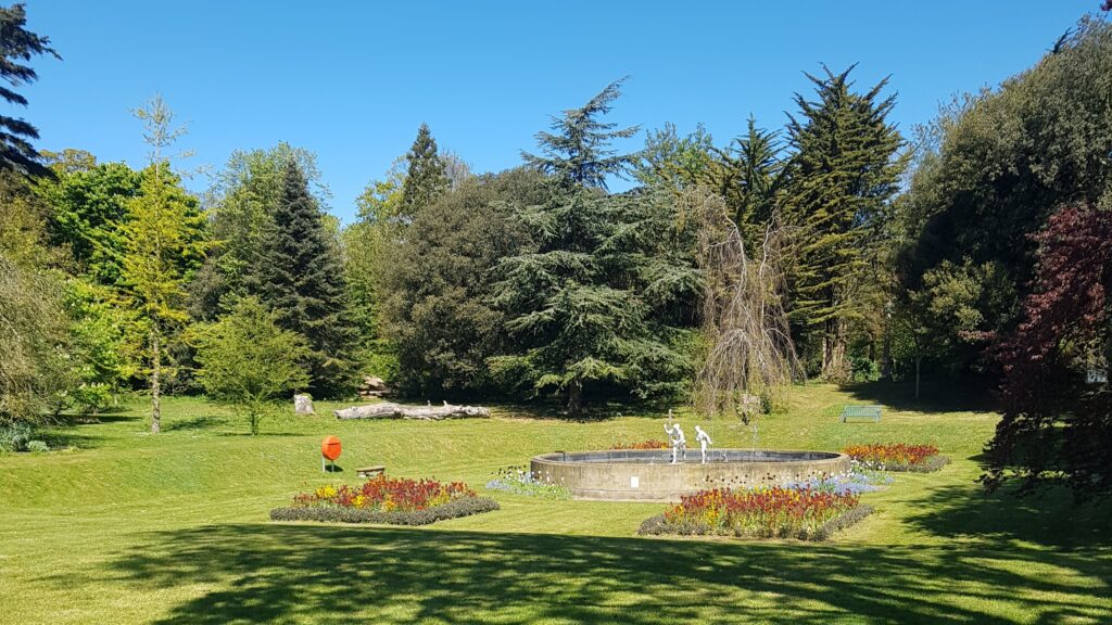 Sunny large country house garden of trees, lawns and flowers plus pond with water feature