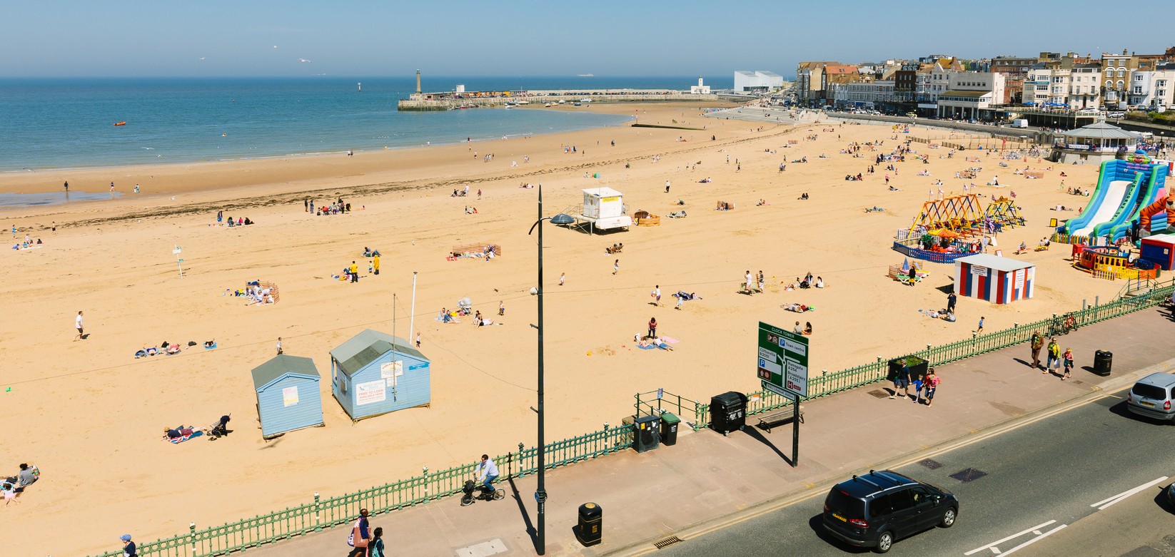 Aerial view of sandy beach with children's rides, tide out and looking across to harbour arm and Turner Contemporary